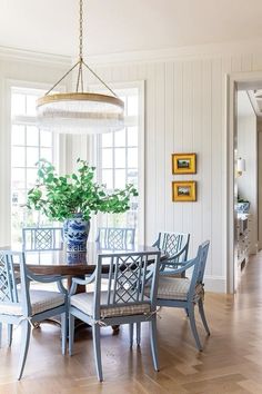 a dining room table with blue chairs and a potted plant on the top of it