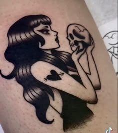 a woman holding a skull and wearing a black dress on her thigh is shown in this tattoo design