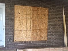 an unfinished wall in front of a brick building with wood planks on the floor