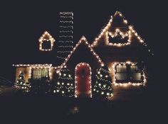 a house covered in christmas lights with decorations on the front and side of its roof