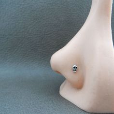 a small white vase with a black and silver nose ring on it's side