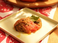 a square white plate topped with food on top of a red and white table cloth