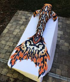 a large piece of art sitting on top of a white tablecloth covered in orange and black designs