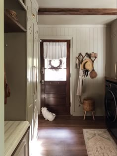 a dog is sitting on the floor in front of a door with a hat hanging from it's side