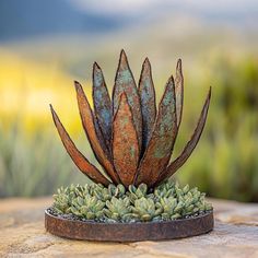 a metal planter sitting on top of a stone slab with succulents growing out of it