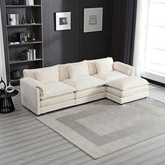 a white sectional couch sitting on top of a wooden floor next to a book shelf