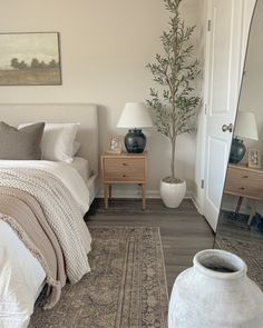 a bedroom with a bed, mirror and vases on the floor in front of it