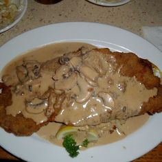 a white plate topped with meat covered in gravy