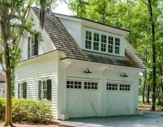 a white house with black shutters and two garage doors on the front door is shown