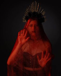 a woman with her hands up in the air while wearing a red veil and headdress