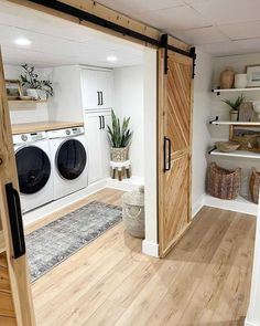 a washer and dryer in a room with wooden floors, white walls and open doors