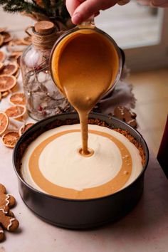 someone pouring caramel sauce into a pan with ginger cookies on the table next to it