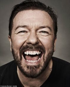 a man with a beard and black shirt is smiling at the camera while he has his mouth open