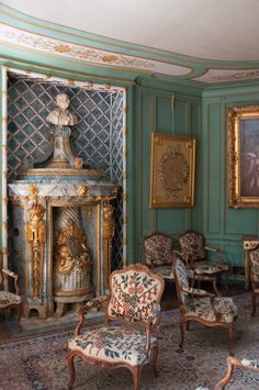 an ornately decorated living room with antique furniture and paintings on the walls, including a fireplace