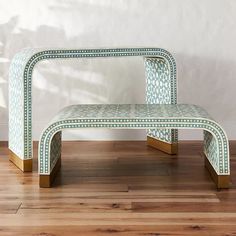 a bench sitting on top of a hard wood floor next to a white and green wall