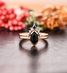 a black diamond ring sitting on top of a table next to other flowers and leaves