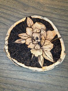 a piece of wood that has been carved into a flower on top of dirt with a skull in the center