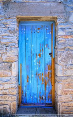 an old blue door is open on a stone building