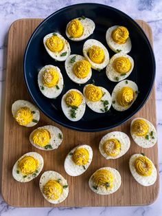 an image of eggs with mustard on them in a black bowl next to other deviled eggs