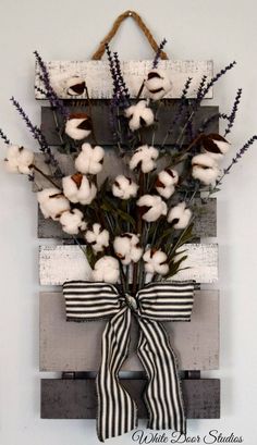 a wooden pallet with cotton flowers and ribbon hanging on the front door to give it a rustic look