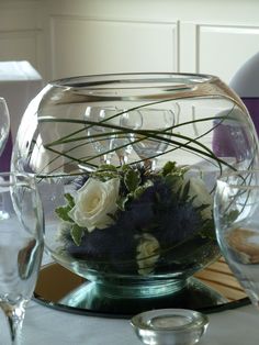 a vase filled with flowers sitting on top of a table next to empty wine glasses