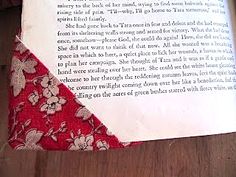 an open book sitting on top of a wooden table next to a red and white flowered cloth