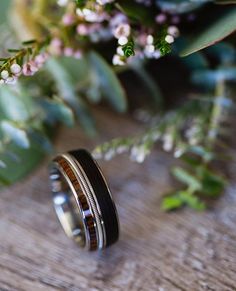 two wedding bands sitting next to each other on top of a wooden table with flowers