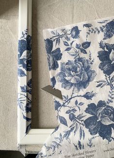 a piece of cloth with blue flowers on it sitting next to a white framed object