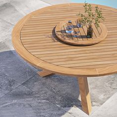 a wooden table sitting on top of a patio next to a swimming pool with plants growing out of it