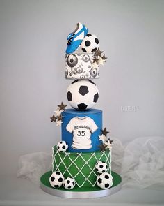 a three tiered cake decorated with soccer balls, stars and a jersey on top