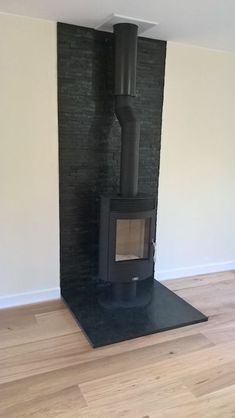 an empty room with a wood stove in the corner and hard wood on the floor