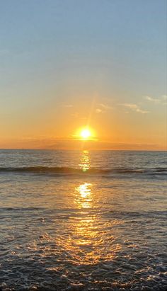 the sun is setting over the ocean with waves