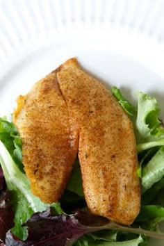 a white plate topped with salad and fried chicken breast on top of lettuce