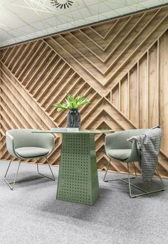 two chairs and a table in front of a wooden wall with geometric designs on it