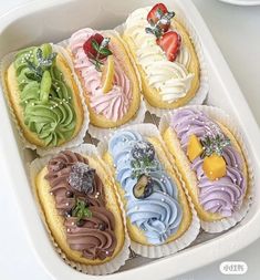 a white tray filled with assorted pastries covered in frosting and toppings