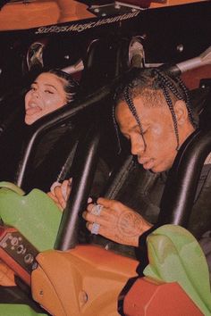 two people sitting in a roller coaster at an amusement park, with one person on the seat