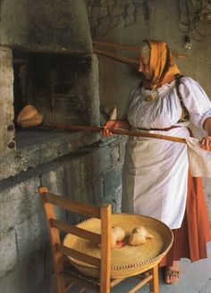 an old woman holding a stick near a chair with two little birds on the seat