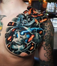 a man with tattoos on his chest has a skull and some other things in the background