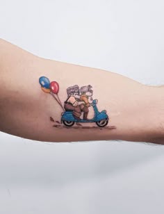 a person with a tattoo on their arm holding a balloon and a teddy bear riding a scooter