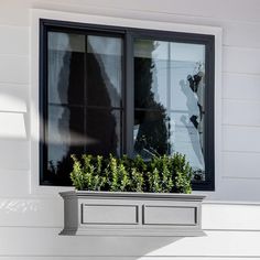 a window sill with plants in it on the side of a white house,