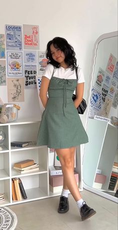 a woman standing in front of a mirror wearing a green and white checkered dress