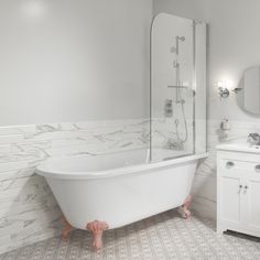 a white bath tub sitting under a bathroom mirror