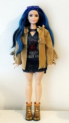 a doll with blue hair and boots standing next to a white wall wearing a jacket