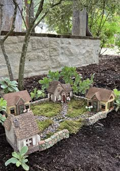 a miniature garden with houses and trees in the middle, surrounded by mulchy grass