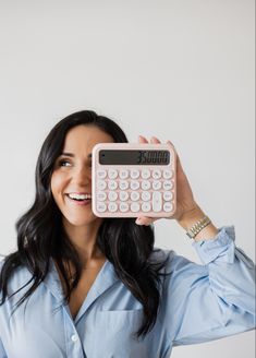 a woman holding up a pink calculator in front of her face and smiling