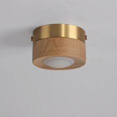 a wooden and brass light fixture against a white wall