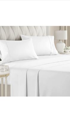 a bed with white sheets and pillows on it