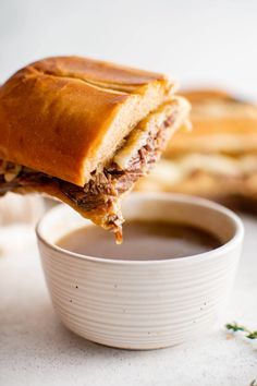 a close up of a sandwich being dipped with dipping sauce