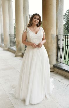 a woman in a wedding dress posing for the camera with her hands on her hips