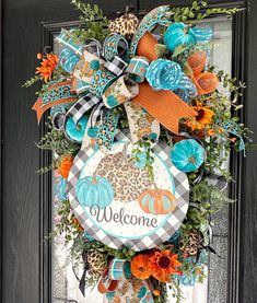 a welcome wreath hanging on the front door with leopard print pumpkins and cheetah